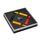 Black TR90 watch with skeleton dial and four silicon straps in black, red, and two shades of yellow, presented in a box.