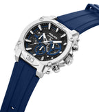 Silver-toned angular watch with black dial, blue subdials, and blue silicone strap. Features a textured crown and pushers.