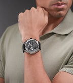 Silver-toned stainless steel watch with a black chronograph dial, silver-toned hour markers, and a black silicon strap.