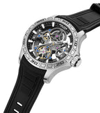 Silver-toned automatic watch with a skeleton dial revealing gears, black outer ring, numbered bezel, and a black textured sil
