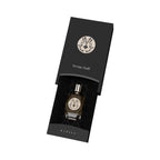 Black box with circular 'M' emblem and 'Incense Oudh' text, holding a dark amber perfume bottle with a gold-toned cap and mat