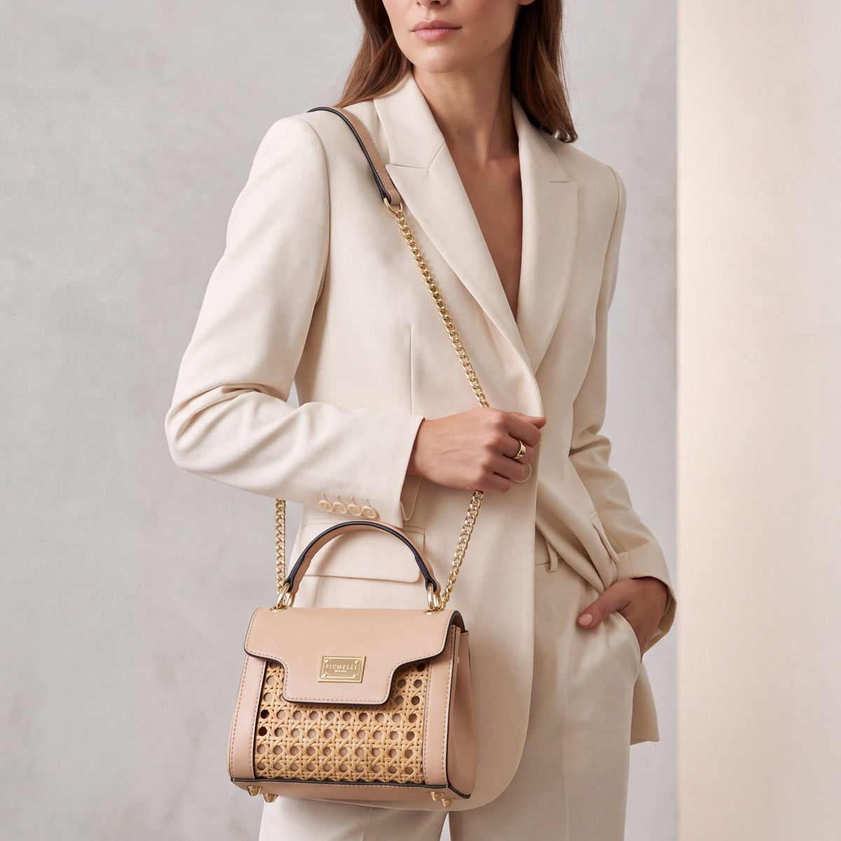 Nude leather and woven cane structured bag with a top handle, front flap, gold-toned hardware, and a chain shoulder strap.