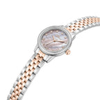 Angled studio perspective accentuating the iridescent luster of the pink mother of pearl face, the brilliant sparkle of the round crystal bezel insert, the rose gold crown accent, and the fluid construction of the two-tone links.
