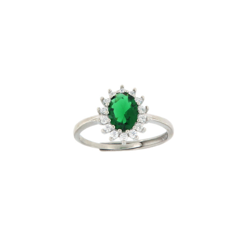 Silver-toned ring with an oval emerald-green stone surrounded by a halo of clear round stones, on an adjustable band.