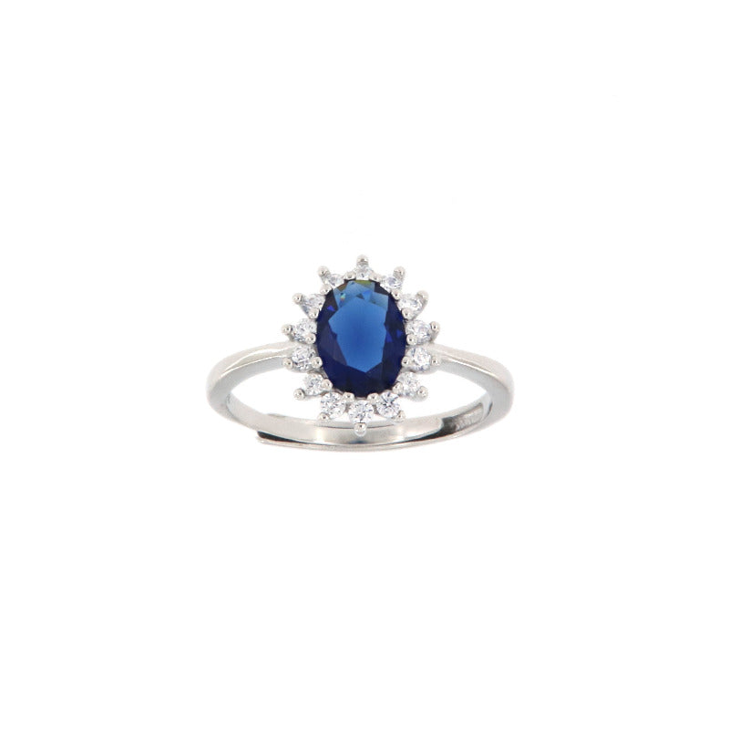 Silver-toned adjustable ring with an oval deep blue stone surrounded by a halo of small clear stones.
