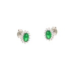A pair of silver-toned stud earrings, each with an oval green stone surrounded by a halo of small clear stones.