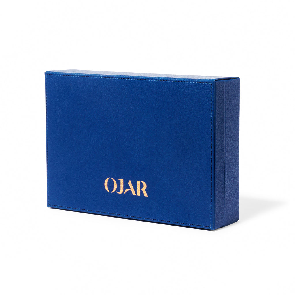 A closed rectangular OJAR presentation box made of premium blue textured leather with the brand name "OJAR" embossed in gold on the front, set against a white background.