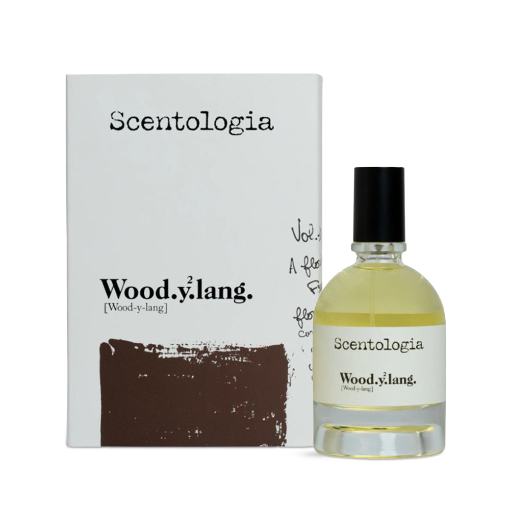 Scentologia Wood.y.lang fragrance, featuring a minimalist glass bottle with a white label and black cap, displayed alongside its artistic branded outer box.