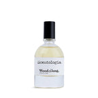 Scentologia Wood.y.lang fragrance, featuring a minimalist glass bottle with a white label and black cap, displayed alongside its artistic branded outer box.