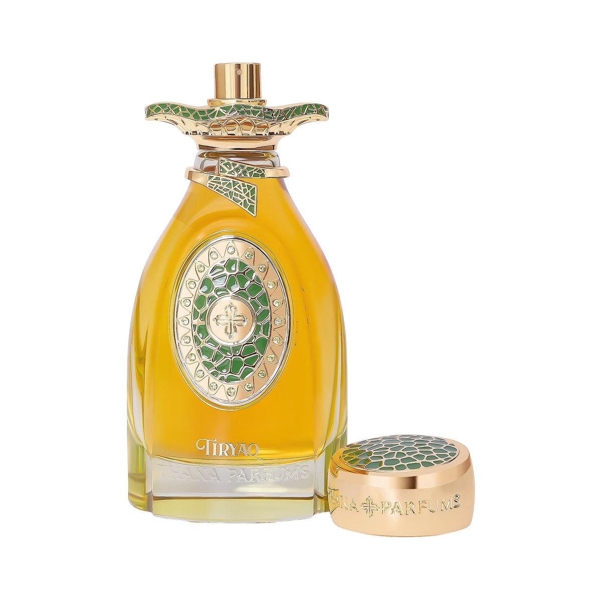 Clear glass bottle with yellow liquid, ornate gold-toned details, and green geometric patterns. Includes a matching gold-tone