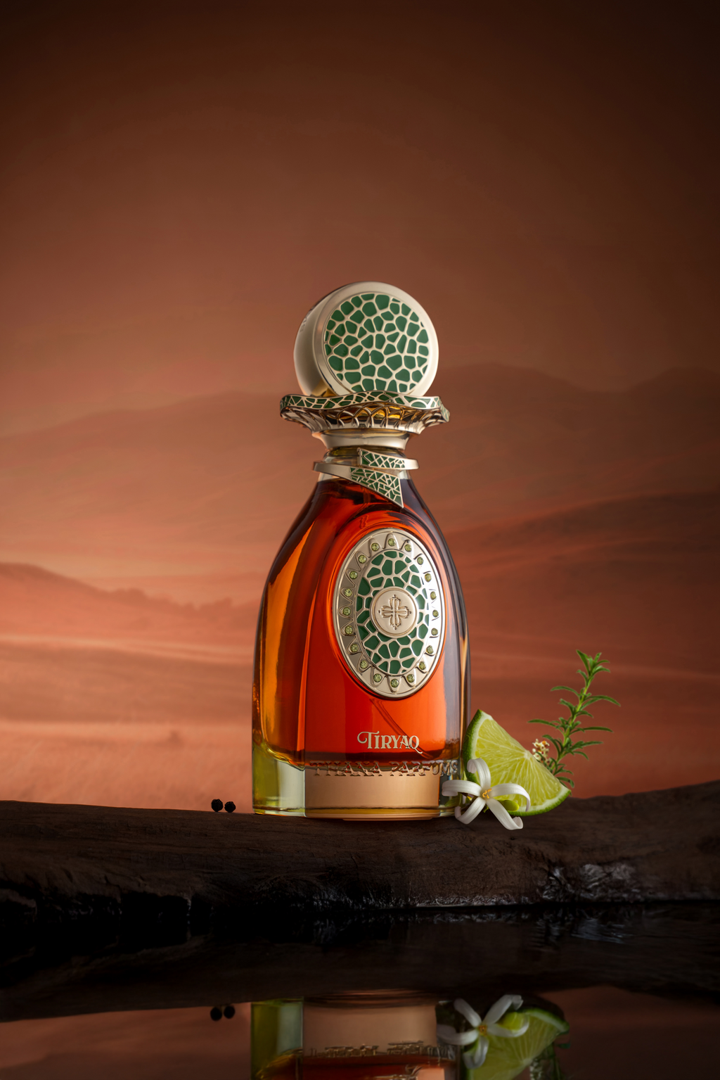 Amber perfume in clear bottle, gold-toned base. Gold-toned oval with green mosaic, central symbol. Gold-toned ornate neck, sp
