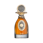 Amber liquid perfume in a teardrop-shaped glass bottle with a dark grey base, ornate gold-toned cap, and black patterned meda