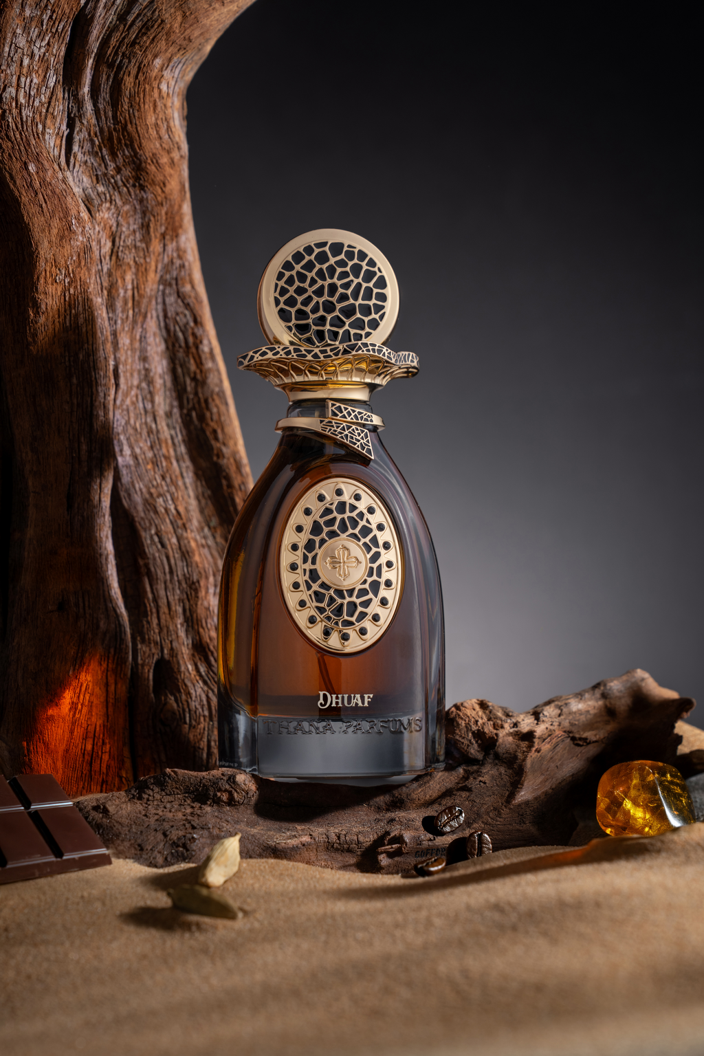 Dark amber perfume bottle with a gold-toned cap and front plaque, both featuring black irregular patterns. Gold-toned ornate