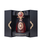 Dark red perfume bottle with an ornate gold-toned cap and label, presented in a black textured box with gold-toned clasps.