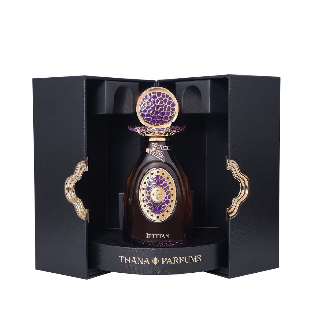 Dark amber perfume bottle with ornate gold-toned cap and purple mosaic top. Gold-toned oval emblem with purple pattern on fro