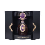 Dark amber perfume bottle with ornate gold-toned cap and purple mosaic top. Gold-toned oval emblem with purple pattern on fro
