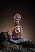 Amber and purple glass perfume bottle with a gold-toned cap. Cap and bottle's oval label feature purple mosaic patterns with