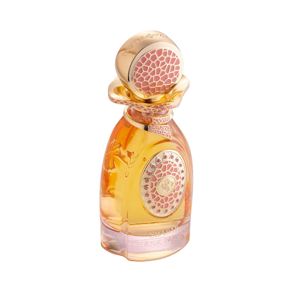 Amber perfume bottle with a gold-toned cap and wavy collar. Pink patterned inserts on the cap and a central emblem with pink