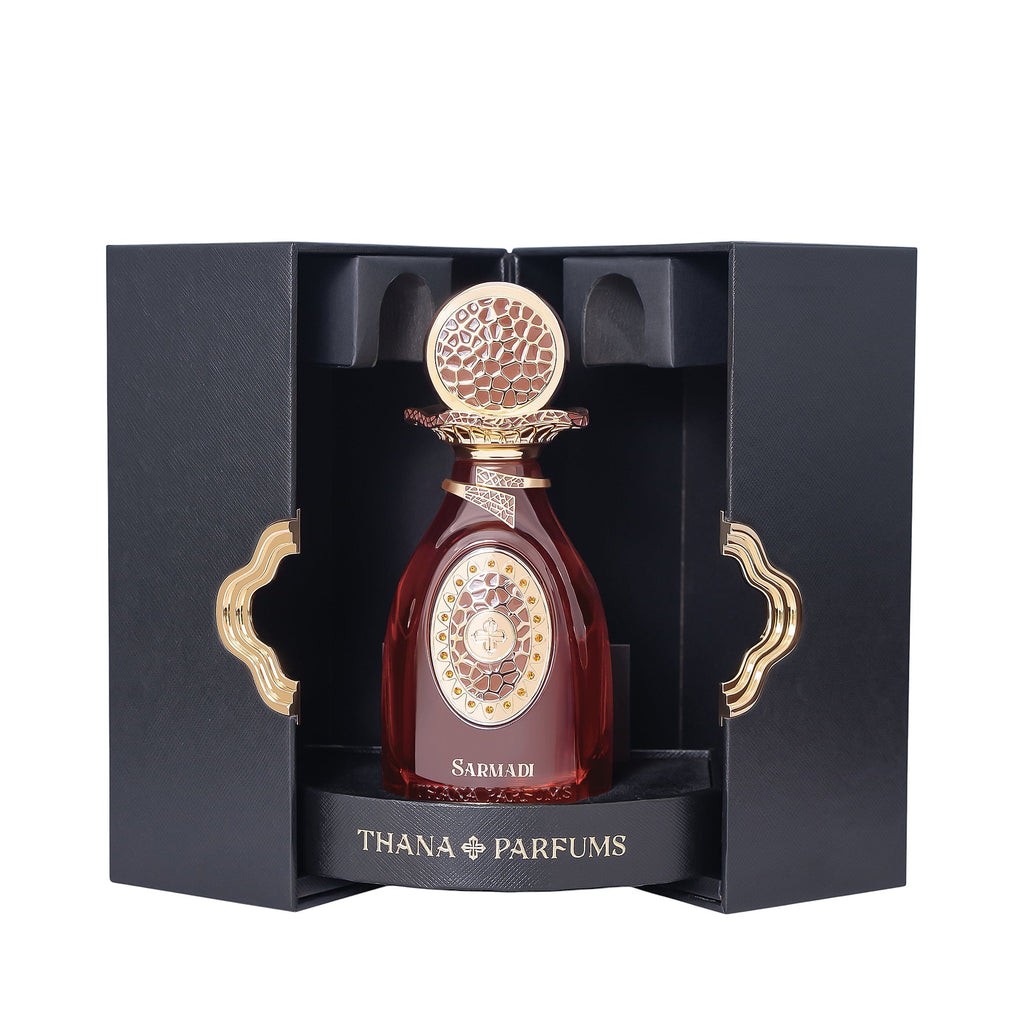 Dark red perfume bottle with gold-toned textured cap, decorative neck, and oval label, presented in an open black box with go