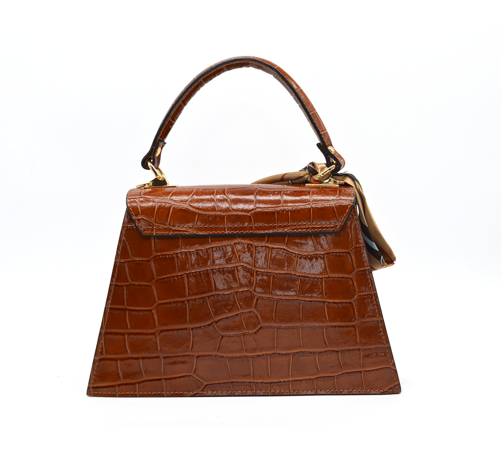Elegant Piumelli handbag in tobacco brown patent croc leather, featuring gold turn-lock, top handle, and silk scarf accent for refined style.