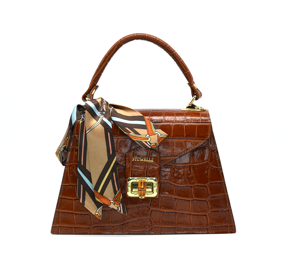 Elegant Piumelli handbag in tobacco brown patent croc leather, featuring gold turn-lock, top handle, and silk scarf accent for refined style.