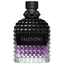 A close-up of a Valentino Uomo Born In Roma Stravaganza fragrance bottle. The glass features the signature rockstud pyramid texture with a gradient transitioning from clear at the base to a vibrant purple in the middle and a deep, translucent black at the top. It is finished with a matte black cap and a black leather-style label with purple branding.