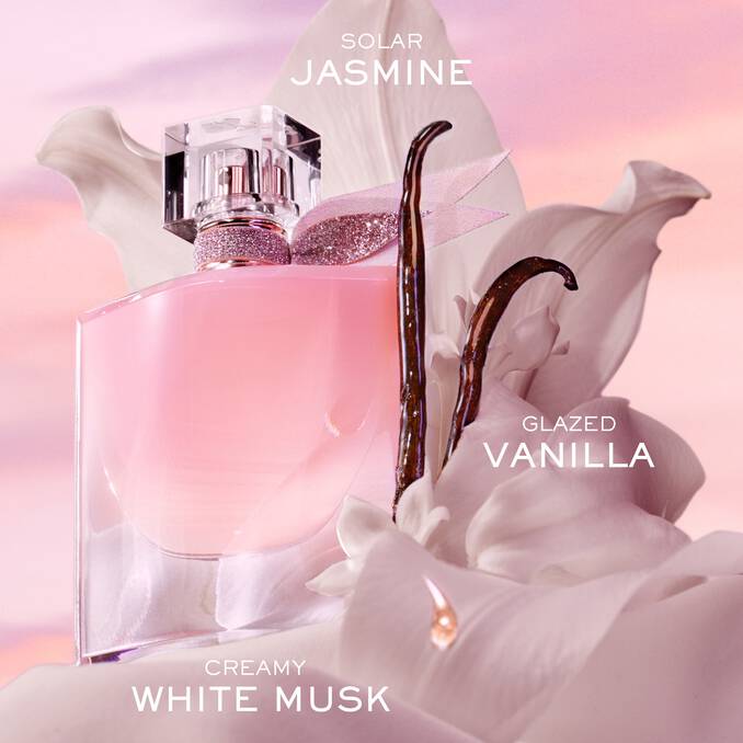 Clear glass perfume bottle with light pink liquid, a glittery rose-gold toned neck, and a clear faceted cap with a pink glitt