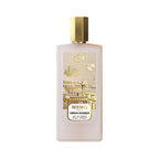 Frosted light pink rectangular perfume bottle with a gold-toned hexagonal cap and a gold-toned label depicting Parisian rooft