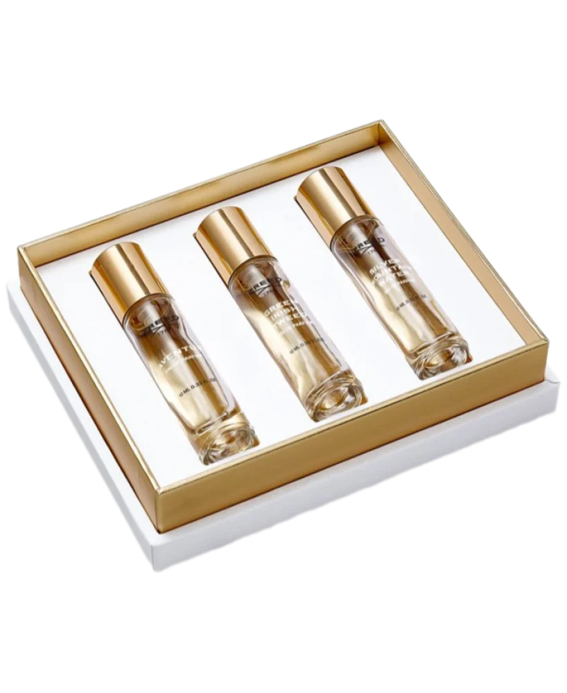 White gift box with gold-toned trim, containing three labeled clear glass fragrance bottles with gold-toned caps.