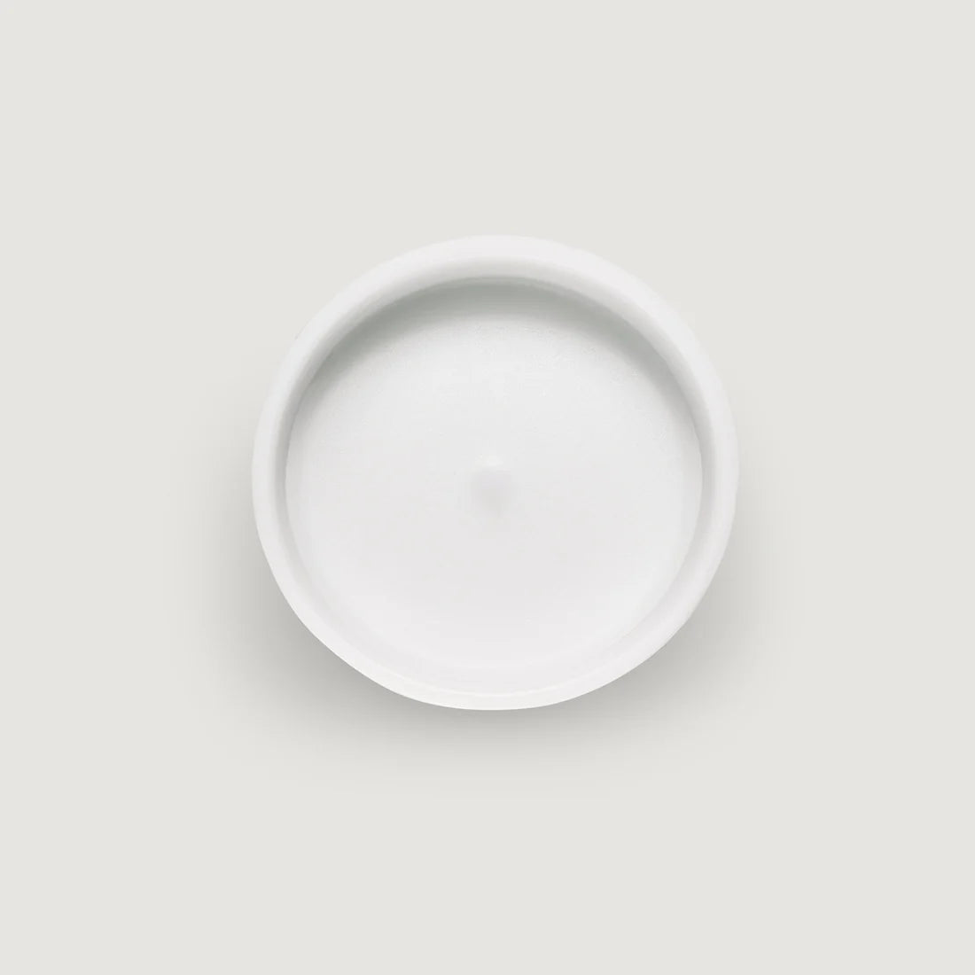 White, circular candle with a smooth, slightly concave top surface and a small central indentation.