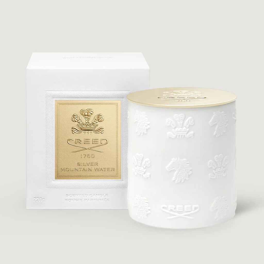 White cylindrical candle with embossed crests and horses, and a gold-toned lid embossed with 'CREED 1760'.