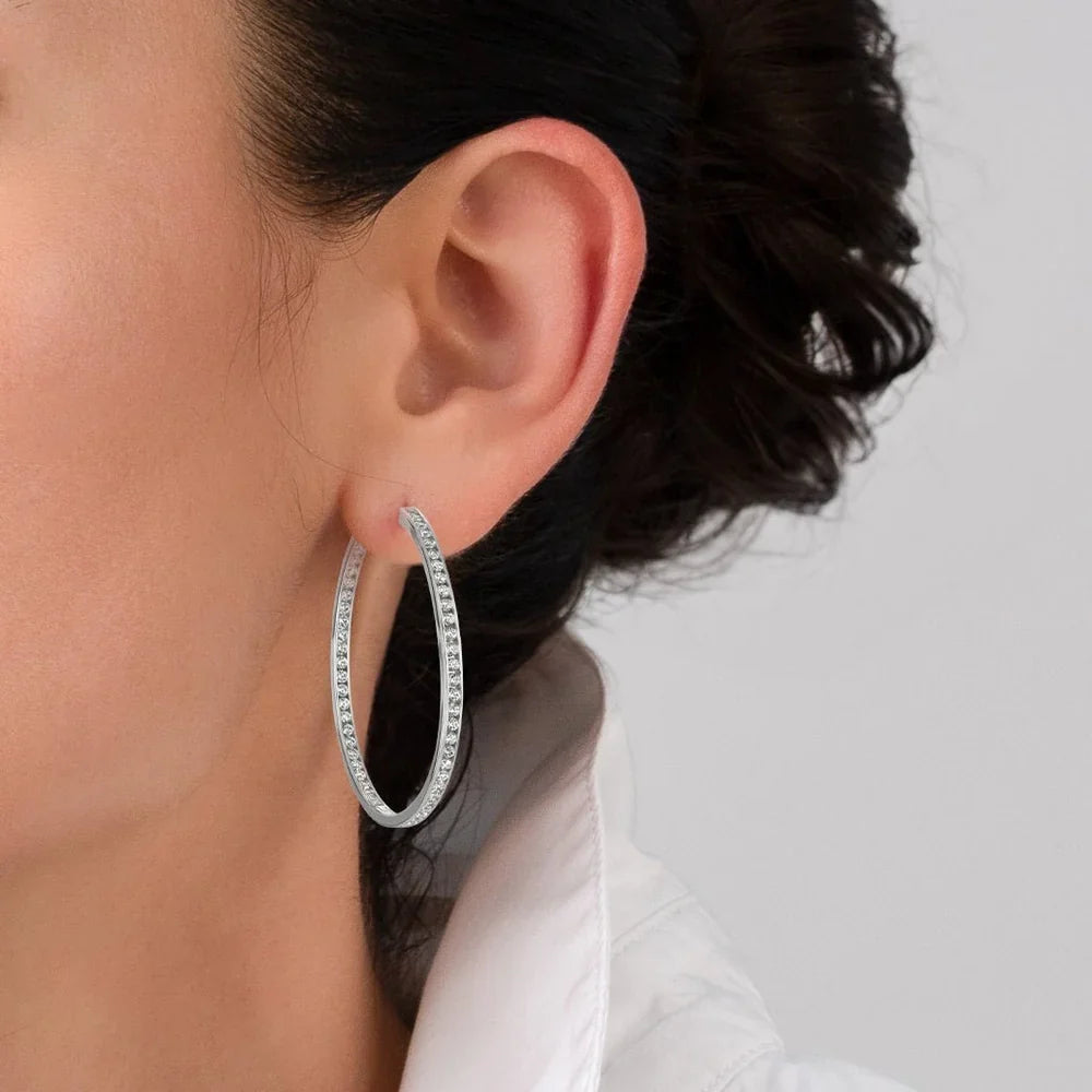 A large, silver-toned hoop earring with clear crystals set along both the outer and inner edges.