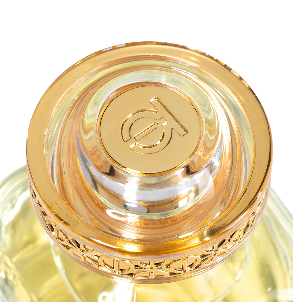 Close-up of a gold and clear cosmetic bottle cap with a brand logo on a white background.